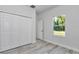 Bedroom features light gray wood floors, closet, and a bright window at 6691 Sw 151Sr Loop, Ocala, FL 34473