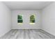 Bright bedroom with light gray wood flooring and two windows at 6691 Sw 151Sr Loop, Ocala, FL 34473