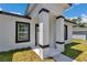 Close-up view of a home's covered porch, showcasing the white pillars, modern door, and black-trimmed windows at 6691 Sw 151Sr Loop, Ocala, FL 34473