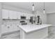 Bright kitchen features white cabinets, stainless steel appliances, quartz countertops, and an island with a sink at 6691 Sw 151Sr Loop, Ocala, FL 34473
