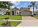 Inviting two-story home with manicured lawn, stone accents, and a brick driveway leading to an attached garage at 724 Duff Dr, Winter Garden, FL 34787