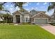 Inviting two-story home with stone accents, lush lawn, and a brick driveway leading to an attached garage at 724 Duff Dr, Winter Garden, FL 34787