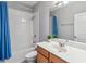 Neutral bathroom with a shower/tub and blue curtains, a toilet, sink and a mirror that reflects the scene at 8160 Iron Mountain Trl, Windermere, FL 34786