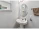 A stylish half bathroom featuring a pedestal sink, an oval mirror, and a neutral color palette at 8160 Iron Mountain Trl, Windermere, FL 34786