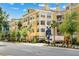 A bright yellow apartment building complex with palm trees and mature shade trees along a city street at 860 N Orange Ave # 323, Orlando, FL 32801