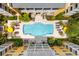 Aerial view of pool with lounge chairs surrounded by tropical plants and yellow condo building at 860 N Orange Ave # 323, Orlando, FL 32801