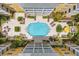 Overhead view of in-ground pool and deck surrounded by lounge chairs, palm trees, and yellow condo building at 860 N Orange Ave # 323, Orlando, FL 32801
