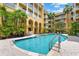 Outdoor swimming pool surrounded by manicured landscaping and yellow building with multiple levels and balconies at 860 N Orange Ave # 323, Orlando, FL 32801