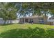A spacious backyard features lush grass, mature trees, a privacy fence, and patio with a screened porch at 10138 Lenox St, Clermont, FL 34711