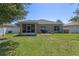 A well-maintained backyard features a lawn, trees, patio area, and screened porch, perfect for relaxing and entertaining at 10138 Lenox St, Clermont, FL 34711