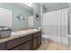 Bathroom featuring double sinks, sleek cabinetry, and a clean shower with a new striped curtain at 10138 Lenox St, Clermont, FL 34711