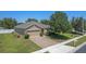 Aerial view showcasing the house, brick paver driveway, manicured lawn, and mature trees at 10138 Lenox St, Clermont, FL 34711