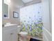 Cozy bathroom features a white vanity, floral shower curtain, and bright natural light from the window at 1161 Coastal Cir, Ocoee, FL 34761