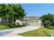 Home featuring a well-kept lawn, mature trees, and an attached two-car garage at 1161 Coastal Cir, Ocoee, FL 34761