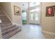 Sunlit foyer with a staircase, tiled floor, and a beautiful entry door at 1161 Coastal Cir, Ocoee, FL 34761