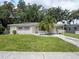 Inviting home featuring pink-accented windows and door, mature trees, a carport, and a well-kept lawn at 1244 Woodland Ave, Lakeland, FL 33801