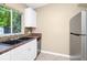 Bright kitchen with updated cabinets, black appliances, double sink, stone tile backsplash, and stainless refrigerator at 1408 Watts Ave, Orlando, FL 32809