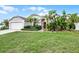 Inviting single-story home showcasing lush landscaping, including palm trees and tropical plants, with green lawn at 145 Henue Ct, Davenport, FL 33896