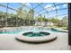 An inviting pool and spa with covered enclosure surrounded by mature landscaping at 145 Henue Ct, Davenport, FL 33896