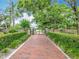 A brick walkway leading to a gate that is surrounded by lush landscaping and mature trees at 148 Tarrytown Trl, Longwood, FL 32750