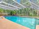Clear blue waters of the inviting screened-in pool, set amidst lush greenery and a serene backyard oasis at 148 Tarrytown Trl, Longwood, FL 32750