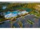 Aerial shot of the community amenities including a pool, clubhouse, parking, and tennis court surrounded by lush greenery at 1590 Contentment Loop, Kissimmee, FL 34744