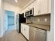 Modern kitchen with stainless steel appliances, white cabinets, gray countertops and tile backsplash at 1590 Contentment Loop, Kissimmee, FL 34744