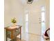 Bright entryway with white tile flooring, a wooden accent table, and a white front door with side windows at 2095 Curry Ln, Orlando, FL 32812