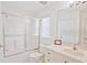 Bright bathroom features a vanity sink, framed mirror, toilet, and tub with sliding glass doors at 2524 Hamlet Ln, Kissimmee, FL 34746
