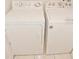 A white, clean washing machine and a clothes dryer appliance stand side by side on the tile floor at 2524 Hamlet Ln, Kissimmee, FL 34746