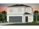 Charming two-story home featuring a modern garage door, lush landscaping, and classic architectural details at 3440 Haven Side Rd, Davenport, FL 33837