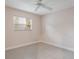 This is a bright, empty bedroom showcasing tiled floors, a ceiling fan, and a window with bright natural light at 3608 Eloise St, Orlando, FL 32806