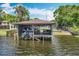 View of covered boat dock with boat lift on waterfront property, featuring seating area and dark water at 3788 N Econlockhatchee Trl, Orlando, FL 32817