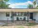 Single-story home with a cozy outdoor seating area on a gravel yard, complemented by lush palm trees at 3788 N Econlockhatchee Trl, Orlando, FL 32817