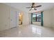 This spacious bedroom features neutral walls, tile flooring, a ceiling fan, and a door leading to a bathroom at 4527 Sandhurst Dr, Orlando, FL 32817
