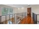 Upstairs hallway featuring hardwood floors, black metal railing, and natural light overlooking the living room at 4527 Sandhurst Dr, Orlando, FL 32817