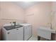 Functional laundry room equipped with a washer, dryer, utility sink, and shelving for storage at 4527 Sandhurst Dr, Orlando, FL 32817