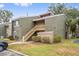 A close exterior view of the condos featuring green facade, wooden staircase and lush green grass at 5071 Eaglesmere Dr # C01, Orlando, FL 32819