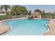 A resort-style pool with a waterfall feature, tanning deck, shade, and lounge chairs offers a relaxing oasis for residents at 5107 Ne 122Nd Blvd, Oxford, FL 34484
