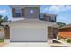 Two-story home featuring a large white garage door and decorative stone accents at 5107 Ne 122Nd Blvd, Oxford, FL 34484