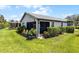 View of a serene backyard with a screened lanai, lush lawn, and well-maintained landscaping at 532 Casanova Ct, Kissimmee, FL 34759