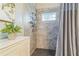 Modern shower with gray tiled walls, glass block window, and chrome fixtures, offering a stylish and functional space at 544 Remington Oak Dr, Lake Mary, FL 32746
