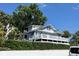 Beautiful two-story home with a white wrap around deck, lush trees, and landscaping at 629 Helen St, Mount Dora, FL 32757