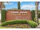 Landscaped community sign provides a welcoming entrance with lush greenery and colorful flowers at 7551 Bear Claw Run, Orlando, FL 32825