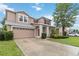 Charming two-story home featuring a red front door, attached garage, and well-maintained landscaping at 7551 Bear Claw Run, Orlando, FL 32825