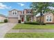 Charming two-story home featuring a red front door, attached garage, and well-maintained landscaping at 7551 Bear Claw Run, Orlando, FL 32825