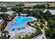 Aerial view of a large community pool, sun loungers and putting green, surrounded by trees and a nearby lake at 809 Benoi Dr, Davenport, FL 33896