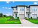 Two-story townhome with a blue front door, two-car garage, and landscaped front yard at 809 Benoi Dr, Davenport, FL 33896