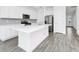 Open kitchen boasts an island, stainless steel appliances, white cabinetry, and wood-look flooring at 809 Benoi Dr, Davenport, FL 33896