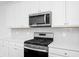 Modern kitchen features stainless steel appliances, quartz countertops, and white cabinets at 809 Benoi Dr, Davenport, FL 33896